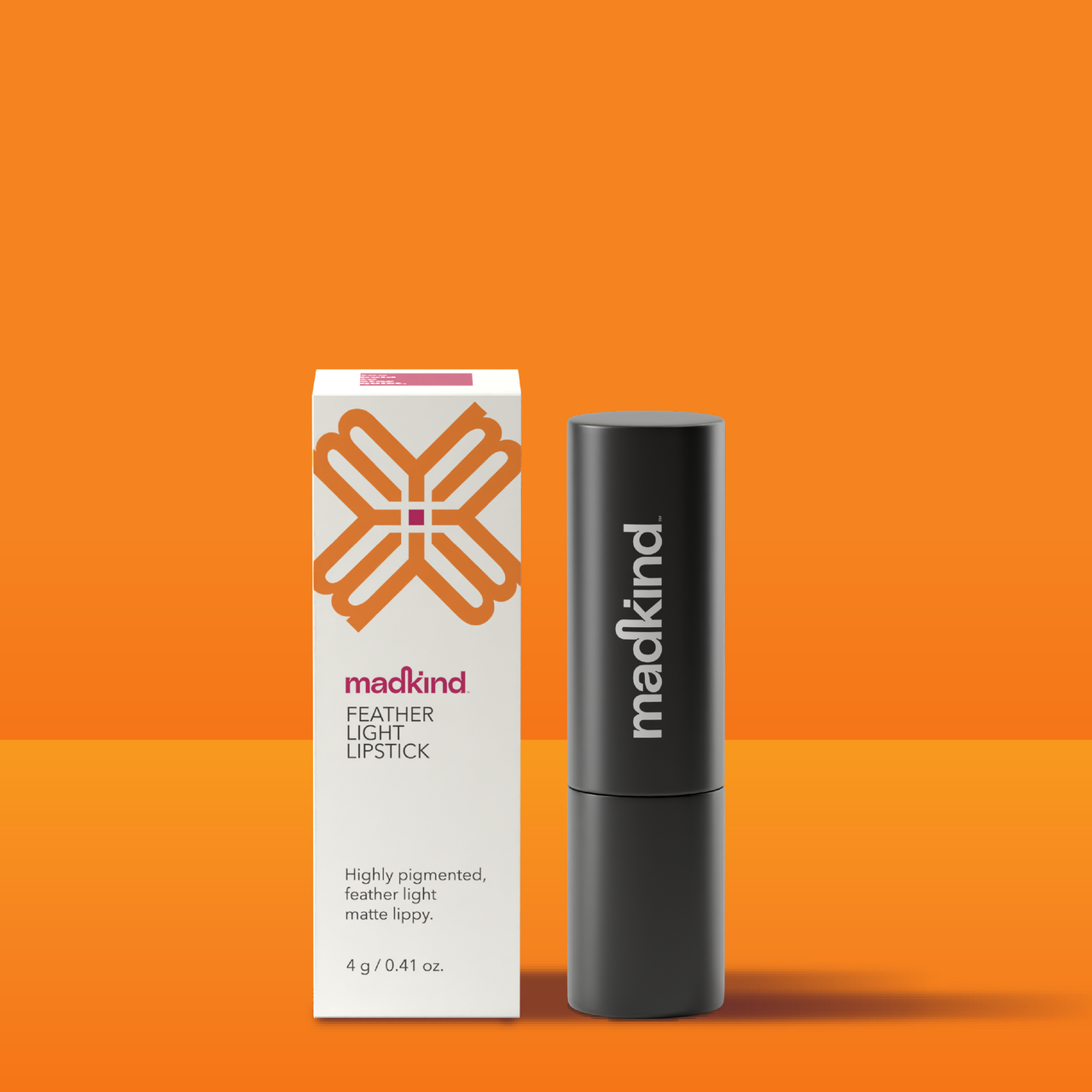 Madkind Feather Light Lipstick and packaging on an orange background